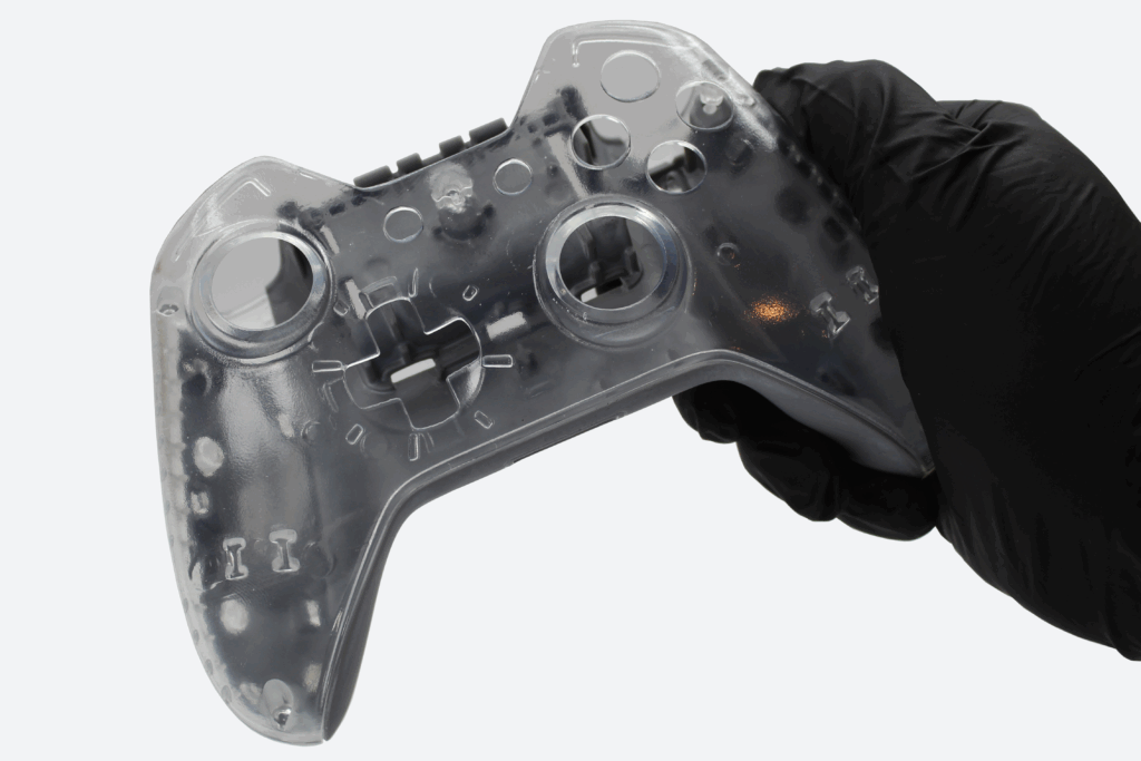 Gloved hand holding a 3D printed video game controller that is clear